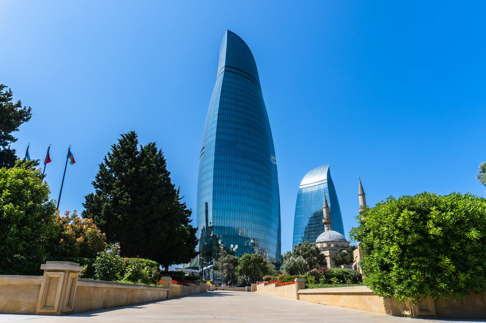 The glass Flame Towers rising above a park in Baku, Azerbaijan, under a clear blue sky