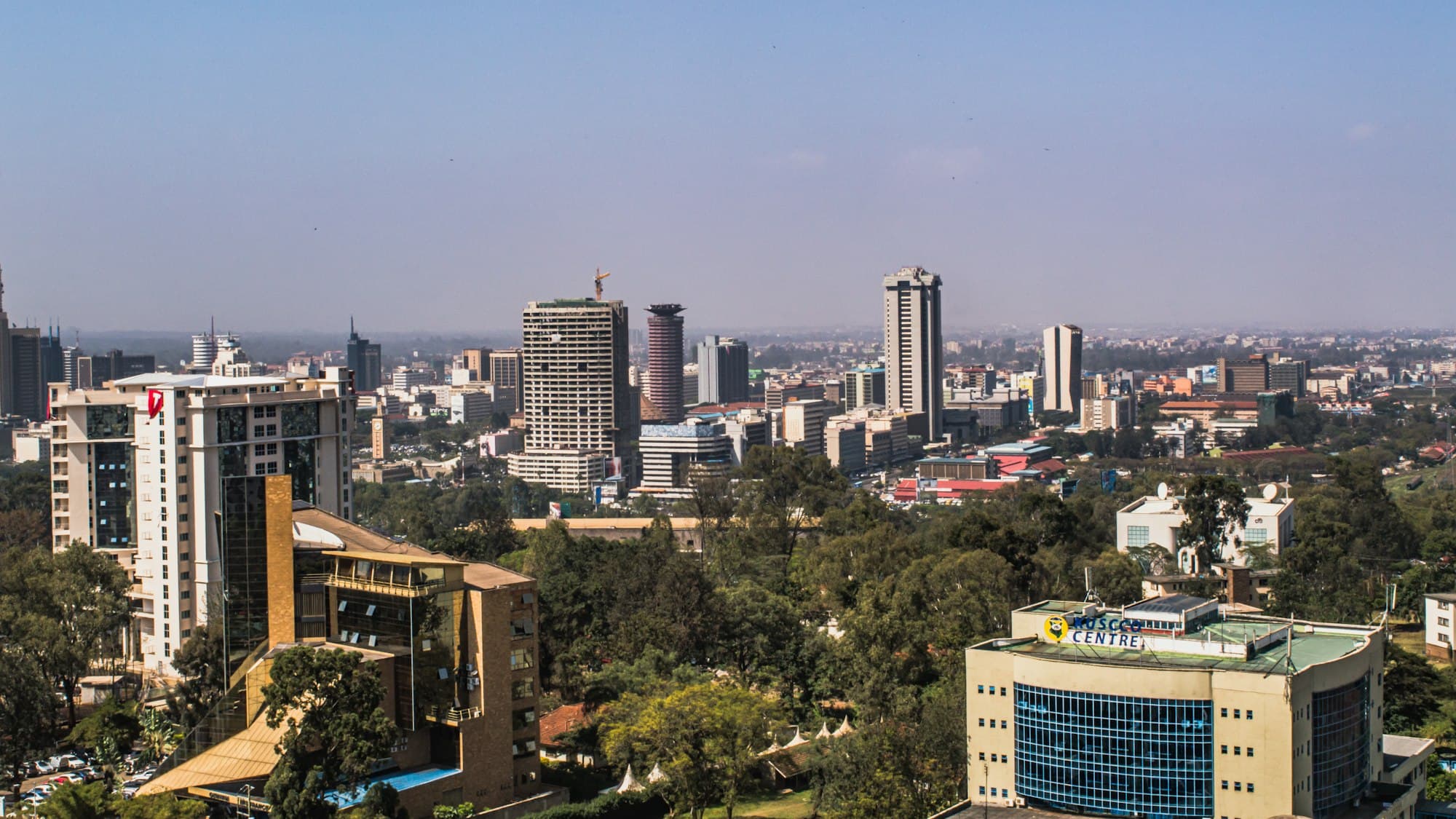 Nairobi skyline, Kenya — modern skyscrapers rising above lush greenery under a clear sky