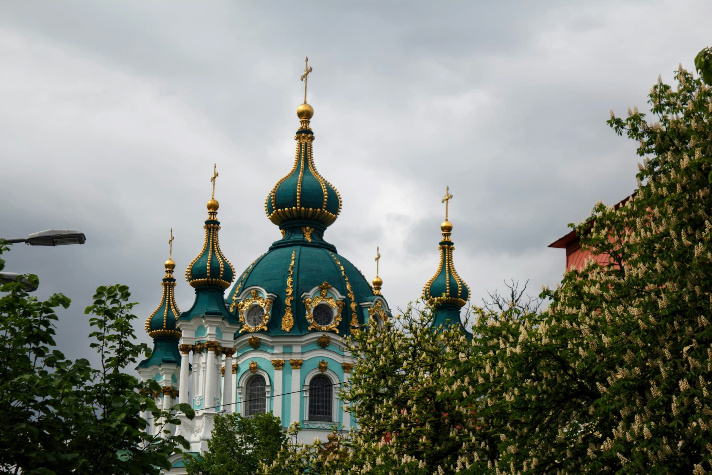 St. Andrew's Church, Kyiv, Ukraine — turquoise Baroque church with gold onion domes rising above the trees