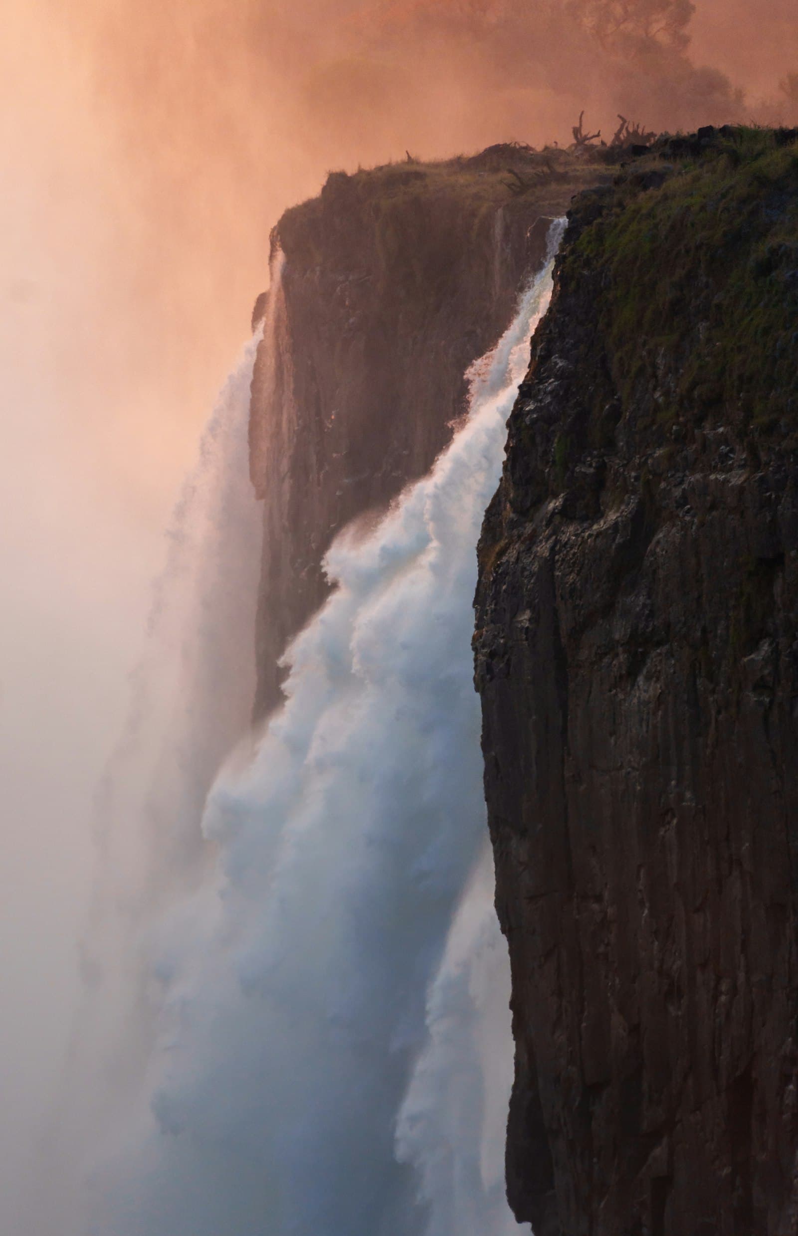 Victoria Falls cascading over the basalt cliffs of the Zambezi gorge at sunset, Zimbabwe